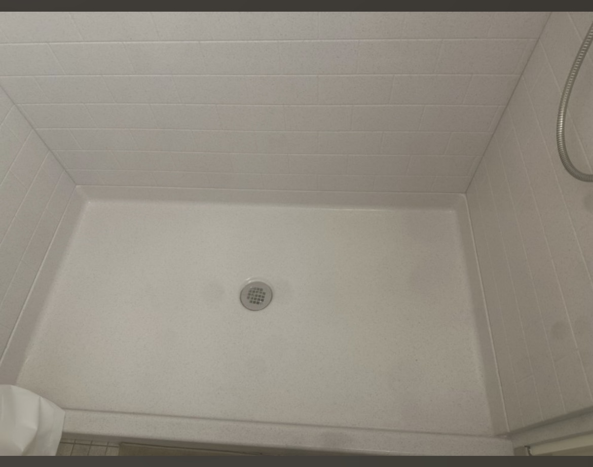 Spotless white walk-in shower floor after deep restoration cleaning
